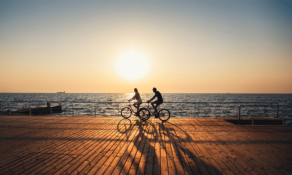 couple riding bikes on beach during sunset